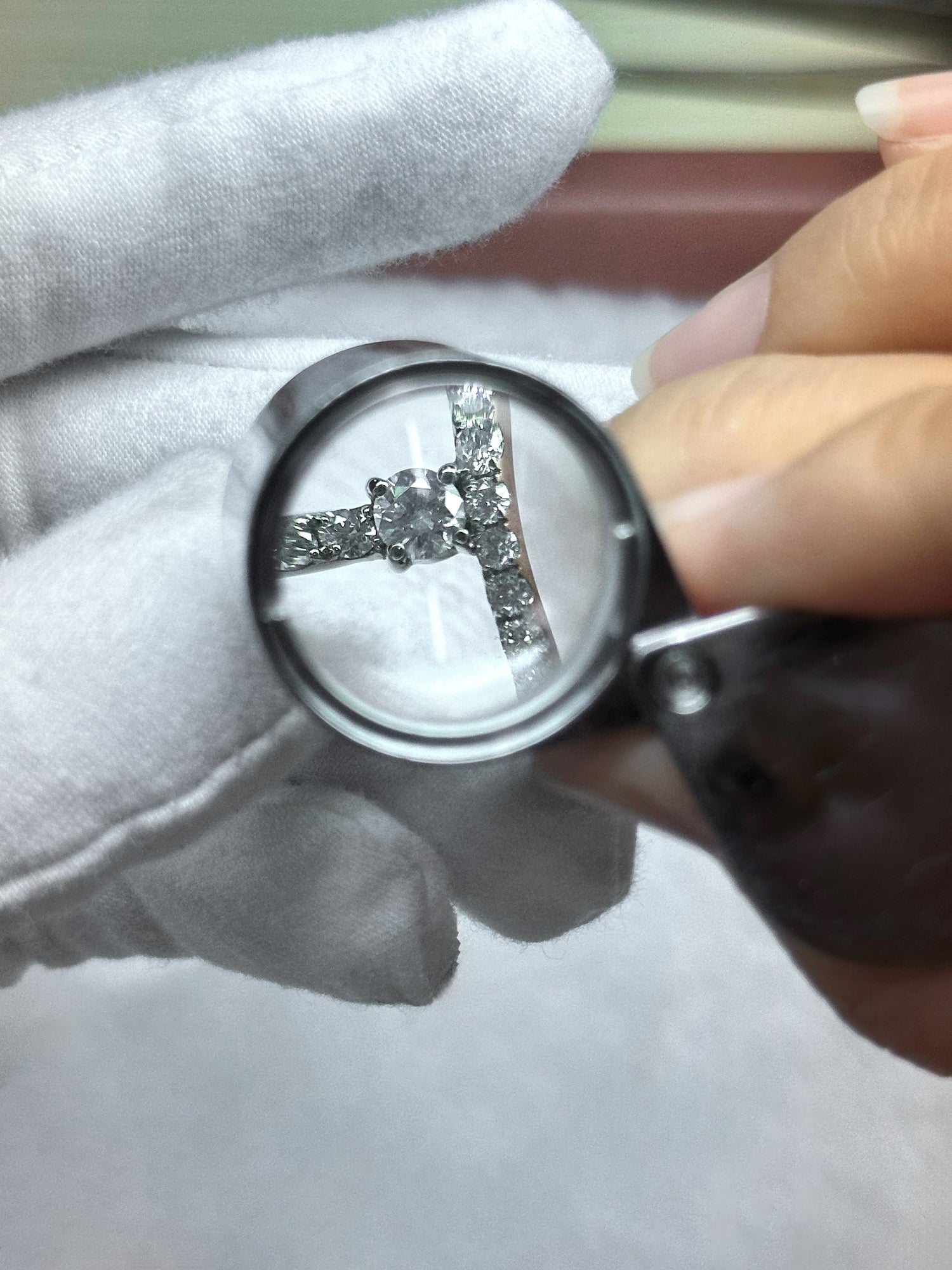 Contrôle qualité d’une bague en diamant avec loupe de joaillier dans l’atelier DYAMKA